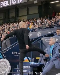 a man kicking a soccer ball on top of a field with people watching in the stands