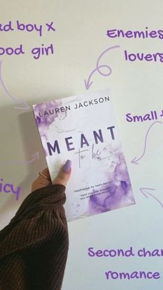 a person holding up a book in front of a wall with words written on it