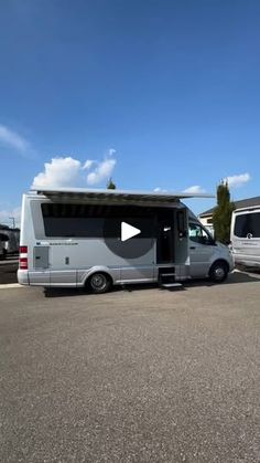 an rv parked in a parking lot next to another van with the door open and windows closed