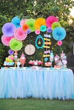 a table topped with lots of colorful paper fans and desserts on top of it