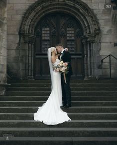 a bride and groom kissing on the steps of an old church