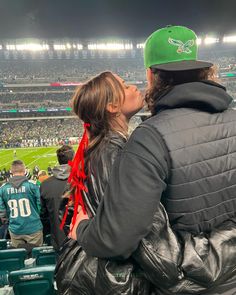 a man and woman kissing in the stands at a football game on a cloudy day