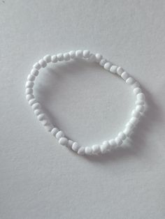 Basic white seed bead bracelet White Beaded Minimalist Stretch Bracelet, Minimalist White Bracelets With Colorful Beads, Minimalist White Beaded Bracelets For Beach, Simple White Round Beads Jewelry, Simple White Round Bead Jewelry, Simple White Round Beaded Jewelry, White Beaded Bracelet With Tiny Beads As Gift, White Beaded Bracelet With Tiny Beads For Gift, White Beaded Bracelets For Jewelry Making With Letter Beads