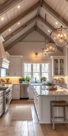 a large kitchen with white cabinets and wood flooring is lit by pendant lights that hang from the ceiling