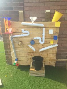 an outdoor toilet made out of wooden pallets with pipes and buckets attached to it