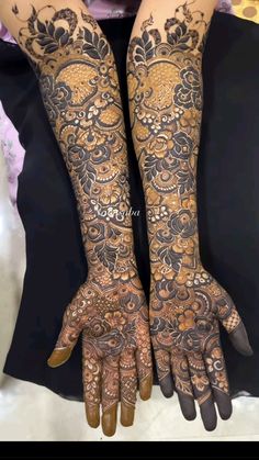 two hands with henna tattoos on them, one is showing off the intricate design