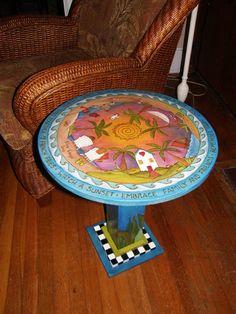 a colorful table sitting on top of a wooden floor next to a wicker chair