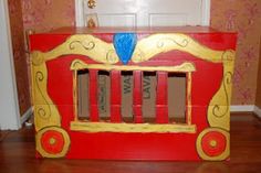 a red and yellow wooden toy box with books in the shape of a firetruck