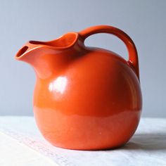 an orange vase sitting on top of a table