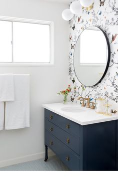 a bathroom with a sink, mirror and wallpaper on the walls is shown in this image