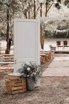 an outdoor ceremony area with white doors and flowers in buckets on the ground next to it