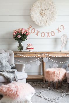 a living room with pink and white decor on the wall, two chairs and a table