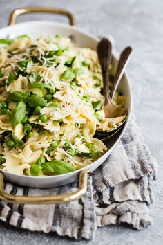 a bowl filled with pasta, peas and parmesan cheese on top of a towel