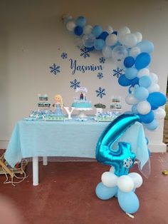 the table is set up for a frozen birthday party with blue and white balloons on it