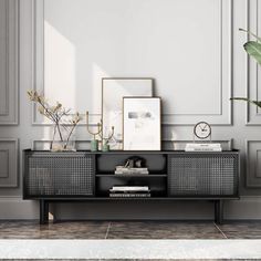 a living room with a plant and some pictures on the wall next to an empty shelf