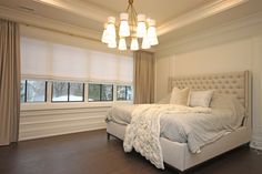 a bedroom with a bed, window and chandelier in the middle of it