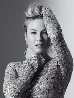 a woman in a gold dress is holding her hands up to her head and looking at the camera