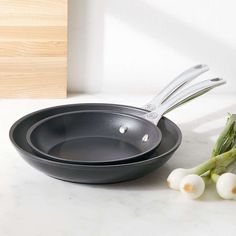 an assortment of cooking utensils sitting on a counter next to some onions and asparagus