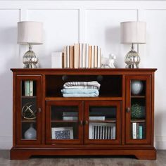 an entertainment center with books, blankets and lamps