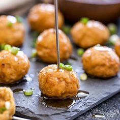 the meatballs are being drizzled with sauce and served on a slate board