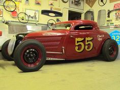 an old red car is parked in a garage