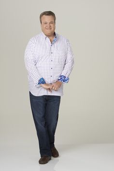 a man standing with his hands in his pockets and smiling at the camera while wearing a white shirt and blue jeans