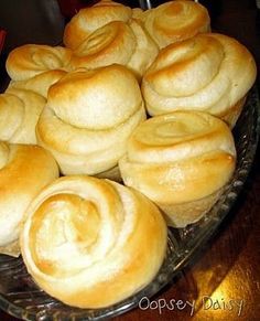 a glass platter filled with rolls on top of a wooden table