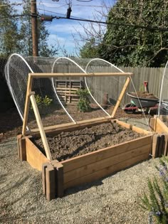 an outdoor garden with wooden raised beds and plants in the middle, surrounded by gravel