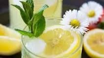 two glasses filled with lemonade and some daisies