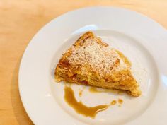 a piece of pie on a white plate with caramel sauce drizzled around it