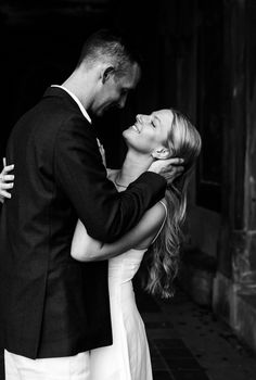 black and white photo of bride and groom embracing each other in front of an old building