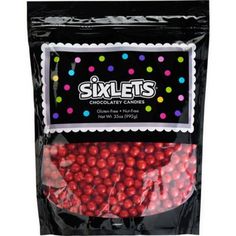 a bag of pink and purple candies with polka dots on the top, in front of a black background