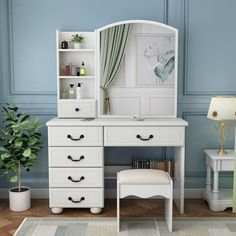 a white desk with drawers and a mirror above it, in a room with blue walls