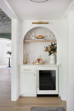 a kitchen with white cabinets and shelves filled with wine glasses