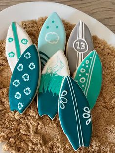 four surfboards are sitting in the sand on top of a white plate with blue and green designs