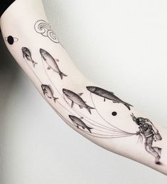 a person with a tattoo on their arm and some fish in the air above them