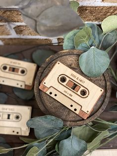 two wooden cassettes sitting on top of a table next to eucalyptus leaves and ivy