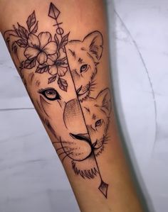 a woman's arm with a lion and arrow tattoo on it, which has flowers in the middle