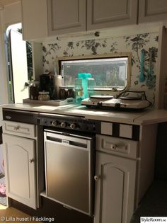 a stove top oven sitting inside of a kitchen next to a sink and microwave under a window