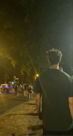 a group of people standing on the side of a road at night