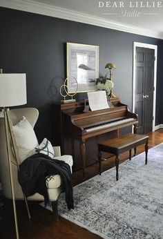 a living room with a piano, chair and rug on the floor in front of it