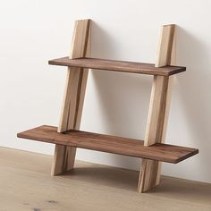 a wooden shelf sitting on top of a hard wood floor next to a white wall