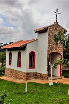 a small church with red windows and a cross on top