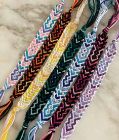 four bracelets with different colors and designs on them sitting on a marble counter top