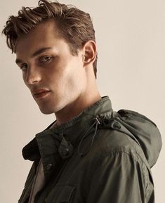 a young man in a green jacket looking at the camera with an intense look on his face