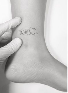 a person is holding their foot up with an elephant tattoo on it