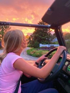 two girls driving a bus at sunset with the sun setting behind them and clouds in the sky