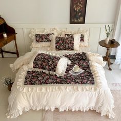 a bed with pillows and blankets on top of it in a room next to a table