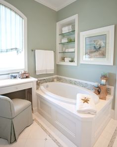 a white bath tub sitting next to a window in a bathroom on top of a tiled floor