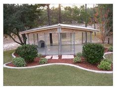 a dog kennel in the middle of a yard with trees and bushes around it